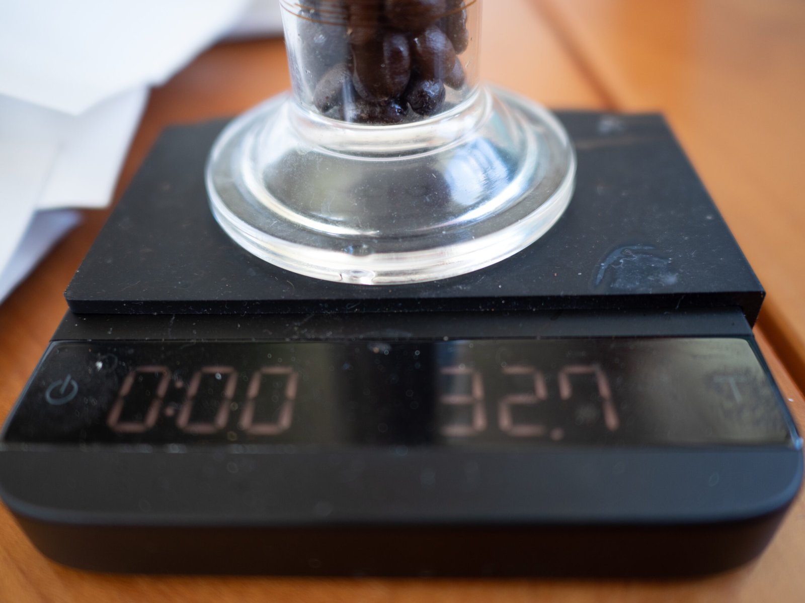 Darkly roasted coffee beans in a 100 ml graduated cylinder on a scale