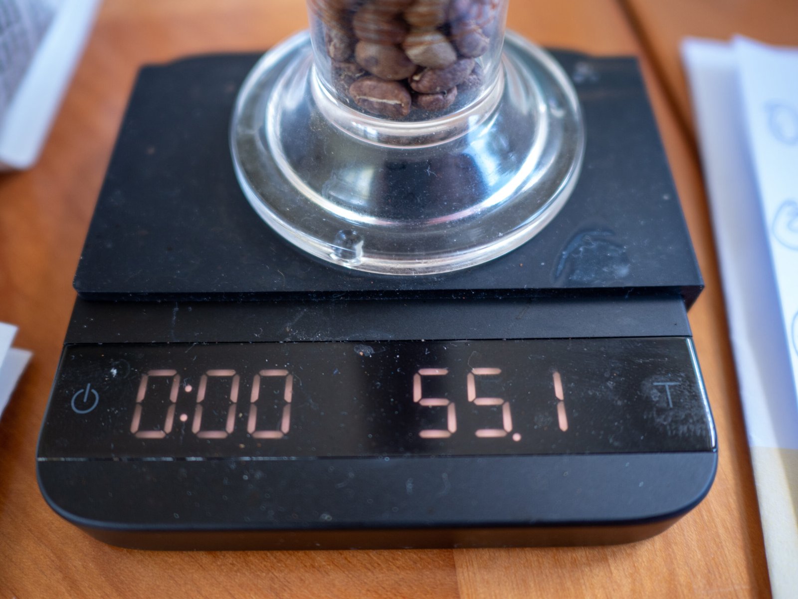 Lightly roasted coffee beans packed level in a 100 ml graduated cylinder on a scale